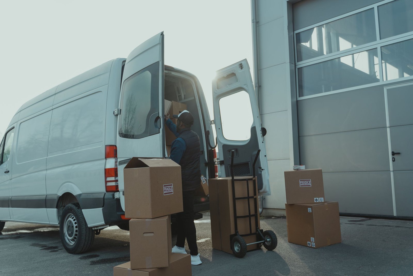 Courier loading cardboard parcels into a white cargo van
